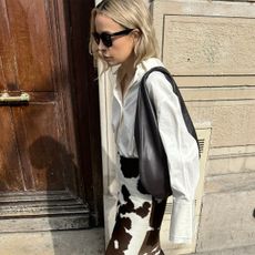 @stephaniebroek wearing a white button-down shirt and cow-print skirt. 