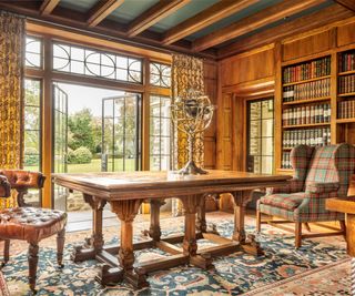 library with fitted bookcases large table and paneled walls with steel framed windows