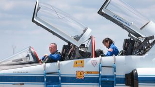 two astronauts in a jet with cockpit covers open