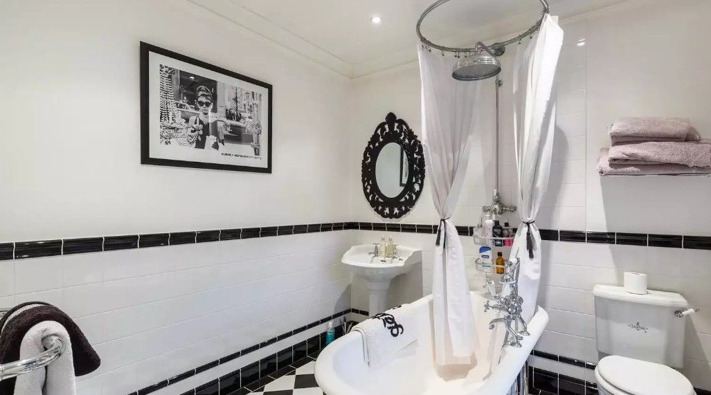 The bathroom shows a black bath and black and white tiled wall