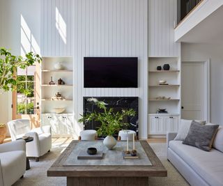 double height living room with white wood paneling and white sofas