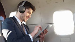 a man wearing the philips ph805 wireless headphones on a plane