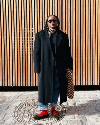 woman wearing cuffed denim outfit with red socks and black mary jane flats