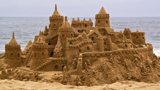 A large sandcastle on a beach with the sea in the background