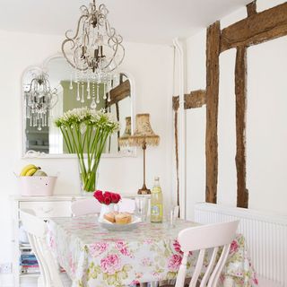 dining area with white wall and flower printed tablecloth and white chair