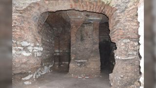 Here we see part of an unground chamber with brick-lined walls and a pillar in the center of the room.