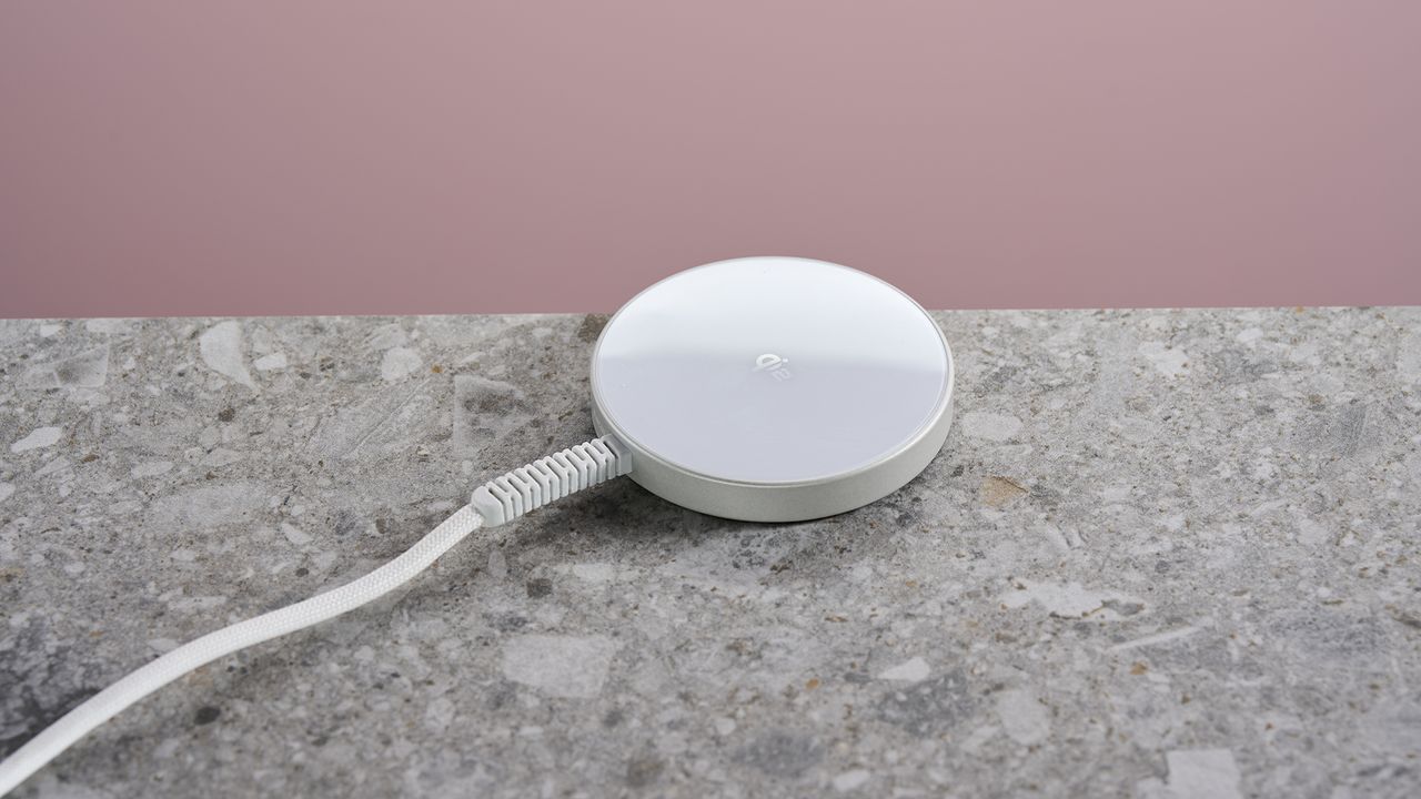 The ESR Qi2 Mini Wireless Charger sits on a light grey stone-effect surface against a pink background.