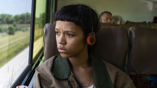 Taylor Russell as Maren with headphones on a bus in Bones and All