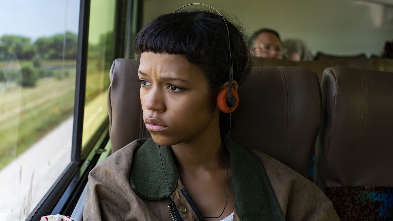 Taylor Russell as Marin with headphones on a bus in Bones and All