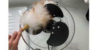 dusting inside a fan with a feather duster to