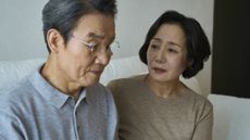 An older woman looks at a serious older man, appearing worried about him.