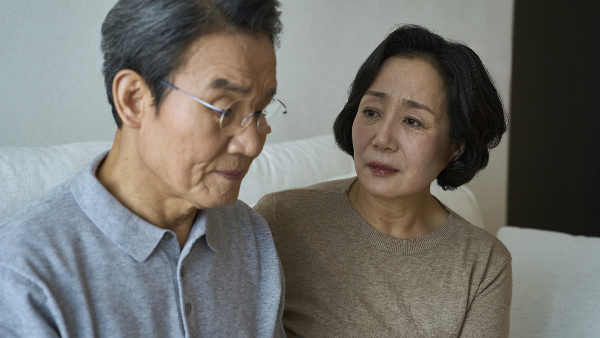 An older woman looks at a serious older man, appearing worried about him.