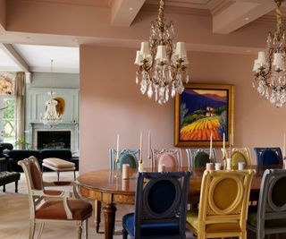 long oval dining table with pink walls and chandelier