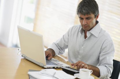 Man using laptop and calculator at desk