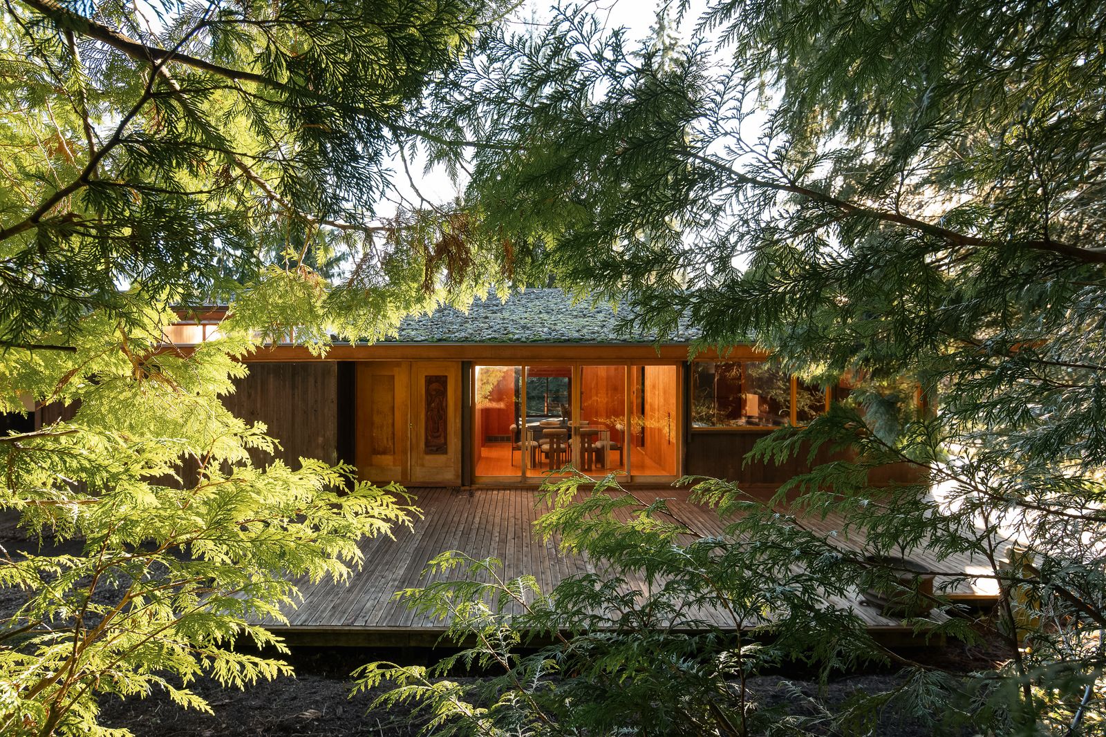 midcentury wooden house glimpsed through trees