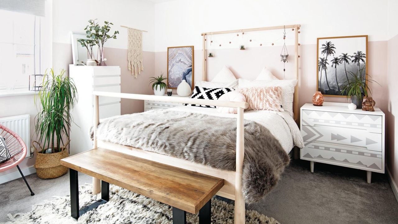 Master teenage girl bedroom with fur throw on double bed, wooden bench and pink and white walls, white and grey chests of drawers as bedside tables. hanging ornaments, fairy lights on the bedhead. 