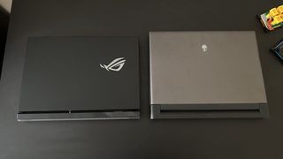 Alienware M18 and Asus ROG Strix Scar 18 laptops on a black desk with lids closed and RGB off