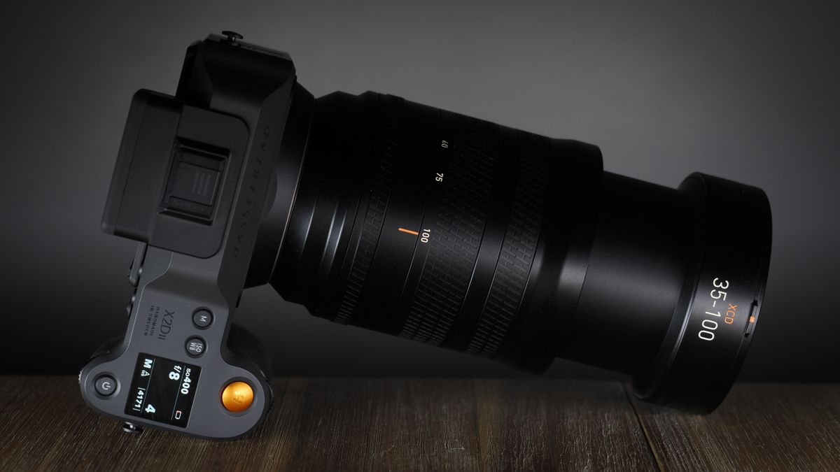 Hasselblad XCD 35-100E lens on a wooden surface in a moodily lit environment