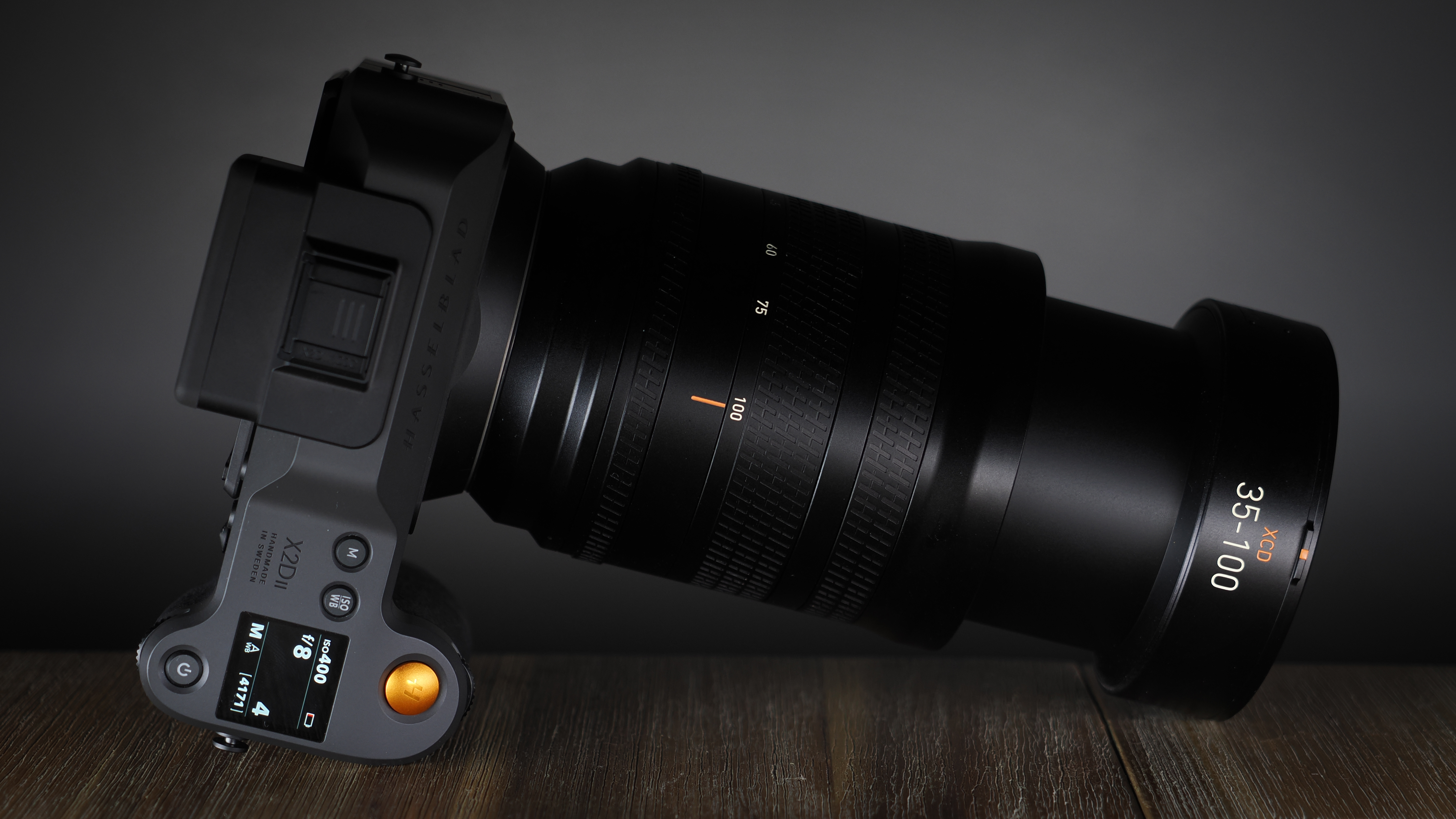 Hasselblad XCD 35-100E lens on a wooden surface in a moodily lit environment