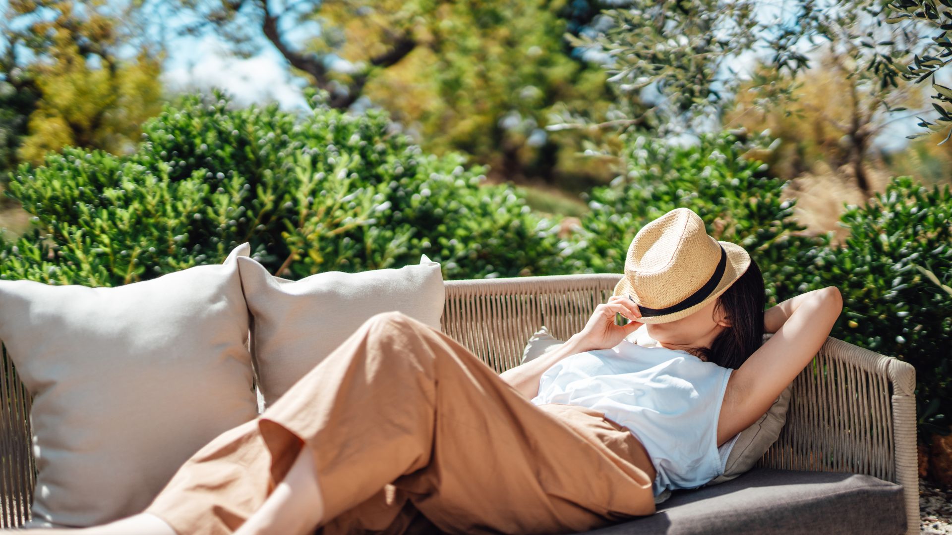 Woman relaxing in her garden, with her hat over her face