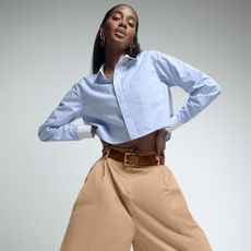 A woman in a shirt and some beige trousers from Good American striking a pose.