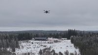A multirotor drone flying over a snow-covered clearing.
