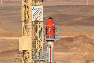 a red capsule sits atop a white rocket on a launchpad