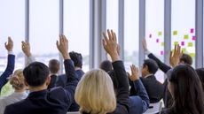 A group of adults facing away from the camera raise their hands.
