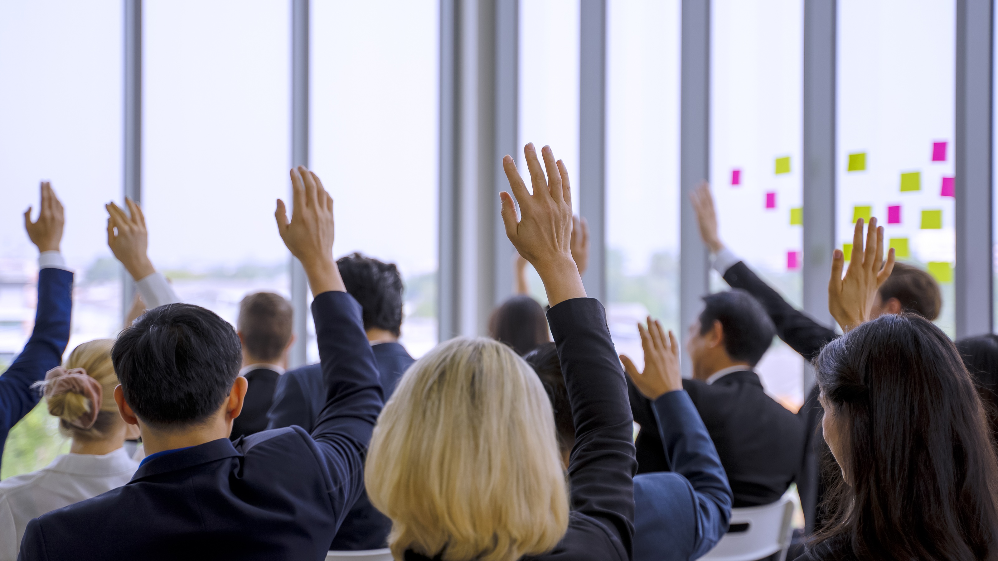 A group of adults facing away from the camera raise their hands.