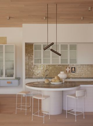 White kitchen with rounded island with brown stone countertop