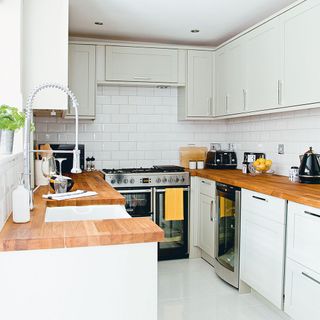 kitchen with white brick designed walls with white cabinet and wooden platform with microwave