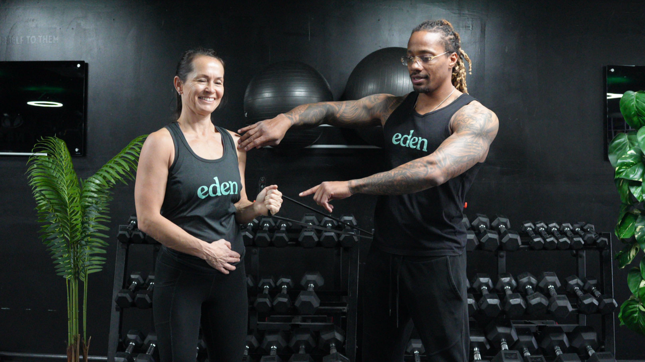 NASM-certified personal trainer Brandon Polk coaches a female client through internal and external shoulder rotations with a resistance band