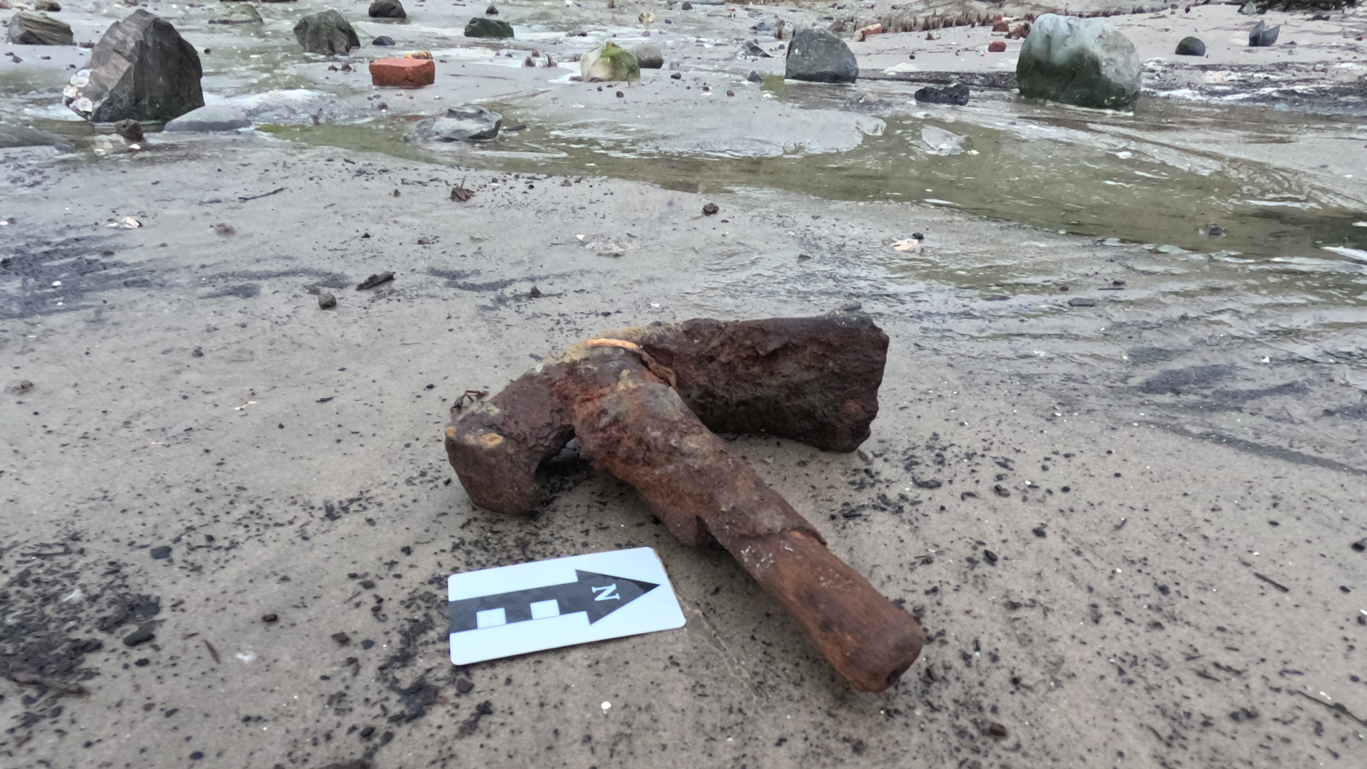 a rusted adze sits on a beach