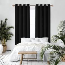 Deconovo Blackout Curtains in bedroom with white walls, lots pf plants, white bedding and wooden bench