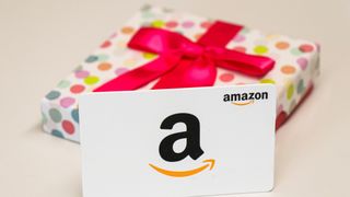 Amazon Gift Card in front of a present wrapped with a red bow