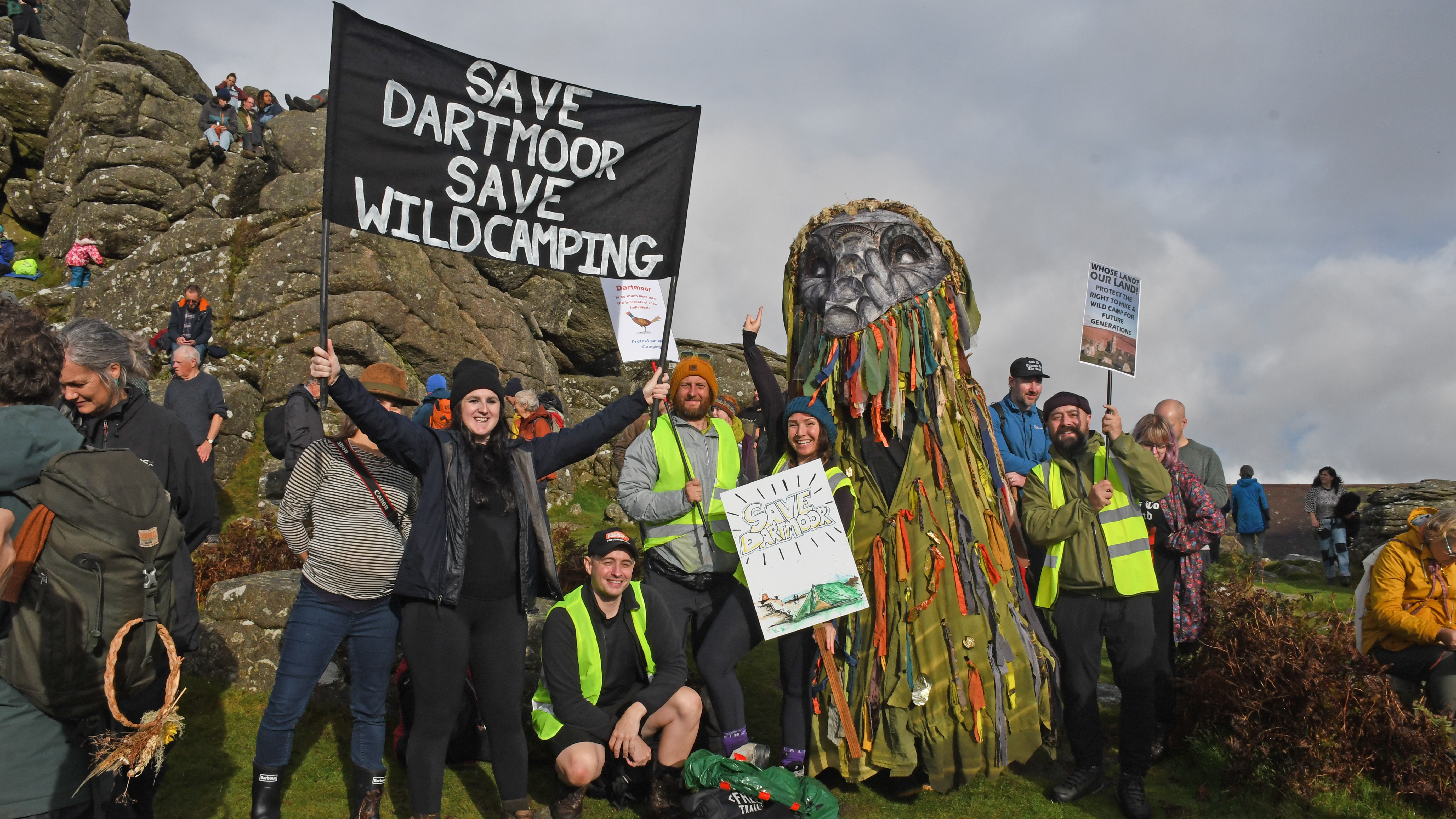 An access campaigner holds a banner saying &#039;Save Dartmoor Save Wild Camping&#039; in front of a crag on Dartmoor National Park during an event in October 2024