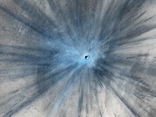 A crater surrounded by streaks of blue-grey