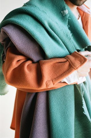 Sander Lak holding fabrics in different colors over his shoulder.