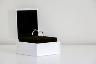 A pair of dainty silver rings in a white ring box with black velvet inside.