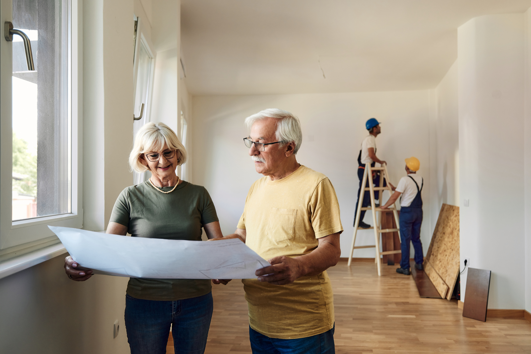 Happy couple reading blueprints during home renovation process.