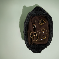 Birds eye view of a selection of gold Astrid and Miyu jewellery in a brown basket