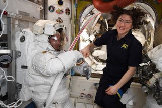 NASA astronaut Christina Koch (right) gives a fist pump to astronaut Andrew Morgan, also of NASA, during a spacesuit check ahead of an Aug. 21, 2019 spacewalk outside the International Space Station.
