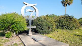 photo of a small monument featuring the number 7 amid bushes and grass