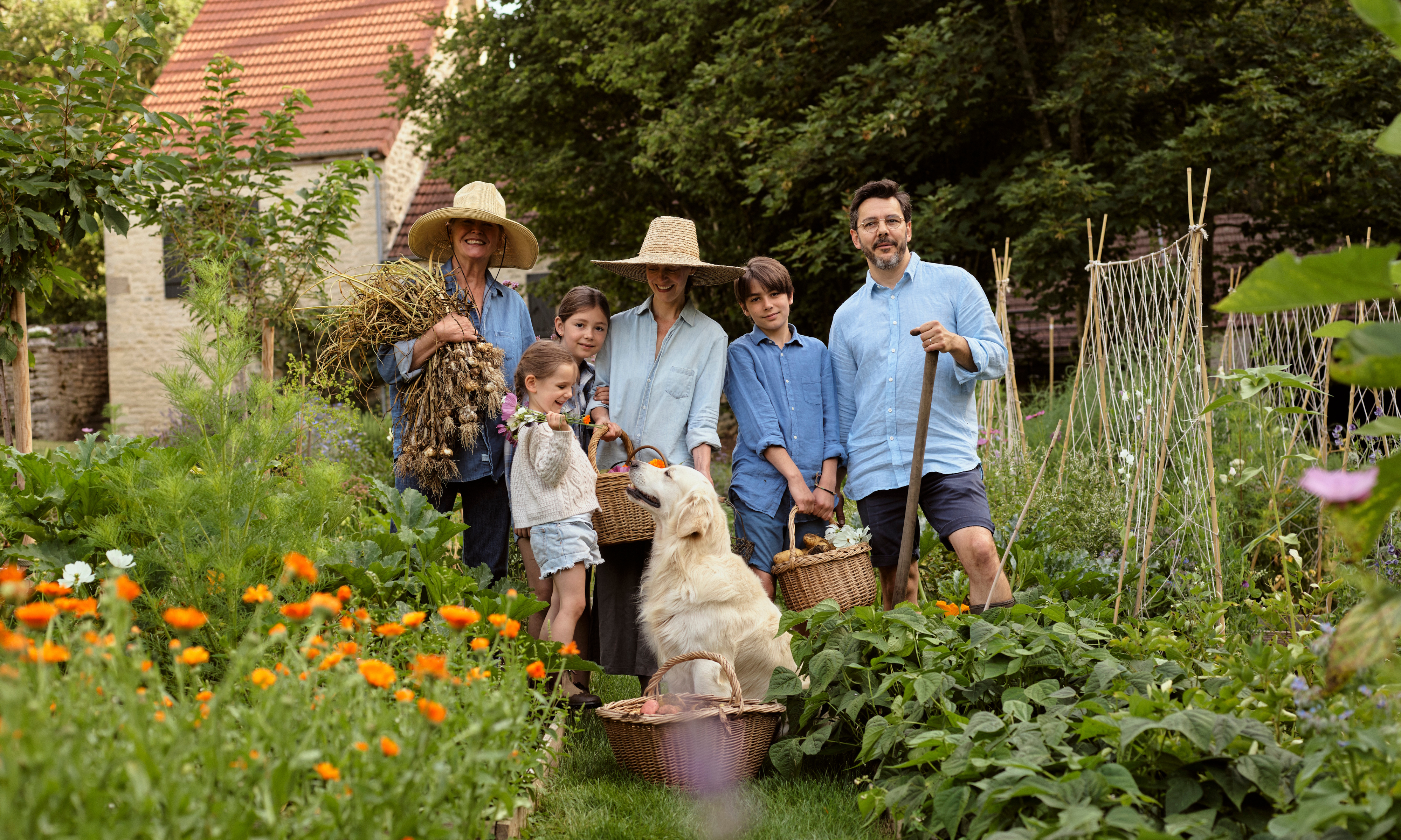 Family and golden retriever dog stood in a kitchen garden in summer