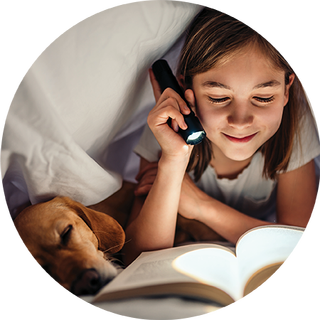 Image of a girls reading her book under the covers with a torch light