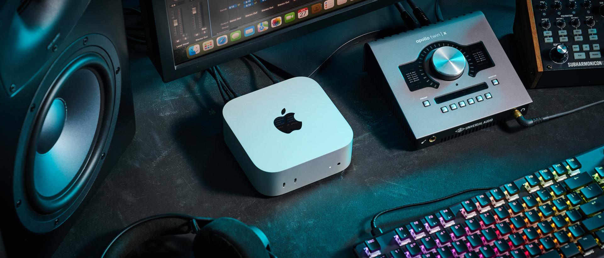 An Apple Mac Mini M4 on a desk with an audio interface, studio monitors, and studio headphones