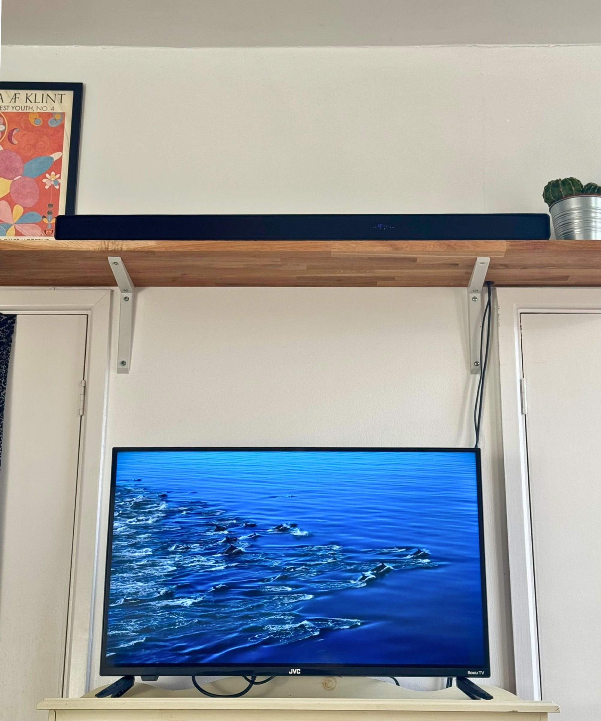Hisense AX5140Q soundbar on wooden shelf, above TV showing fish swimming in blue ocean.