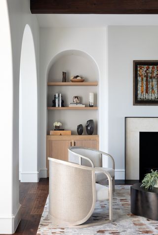 living room with arched bookcase, white chair and patterned rug