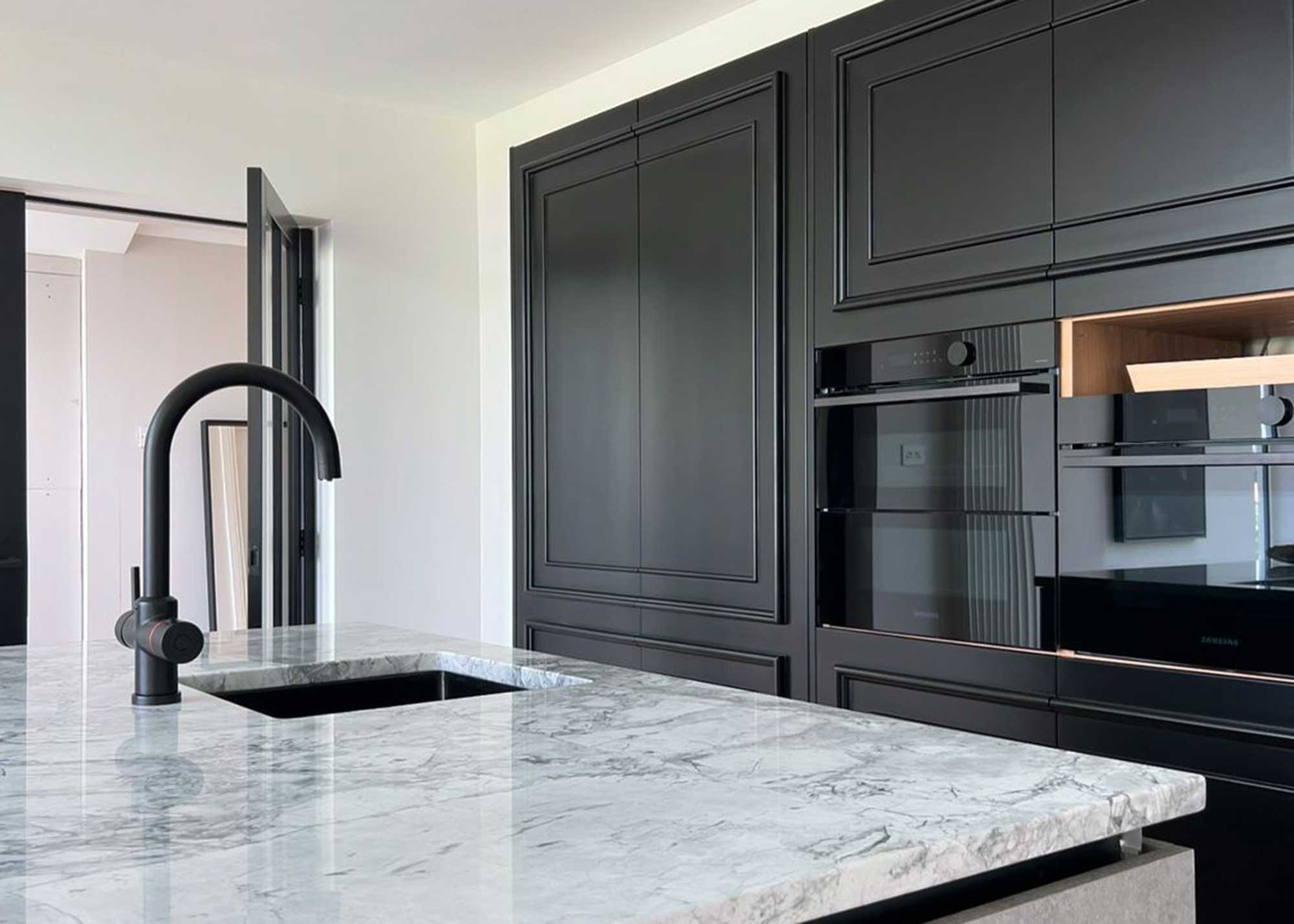 black kitchen with marble work surfaces and matte black tap