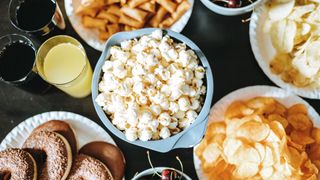 Selection of ultra processed foods, including bowl of popcorn, doughnuts, and crisps